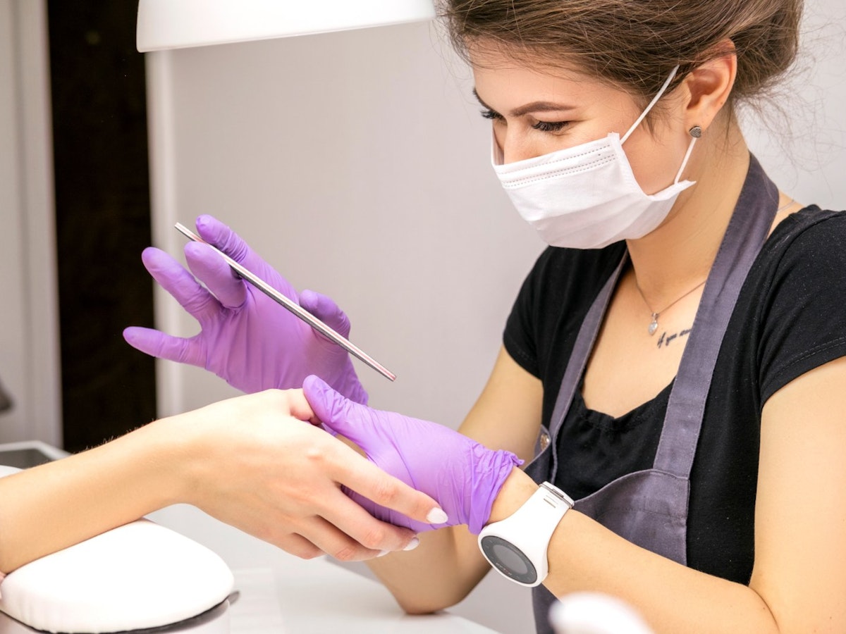 Nail technician providing manicure in a clients home